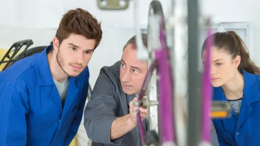 Jeunes en bleu de travail, en formation, avec un professeur, en train de r&eacute;parer un deux-roues