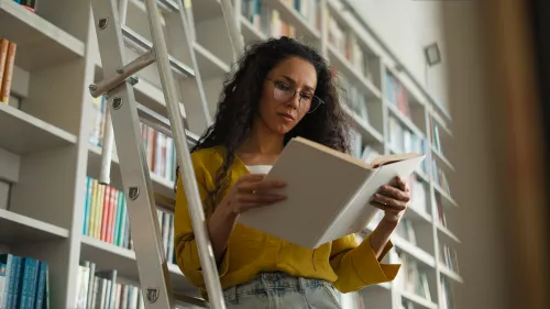 Latina Indian Hispanic woman female student high school university learning girl studying library standing stairs librarian search book textbook pages college teacher learner bookstore buyer archive